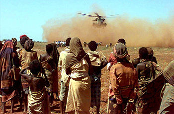 Somalis and Australian Army soldiers wait near the loading zone of a US Marine CH-53 Sea Stallion delivering Australian wheat